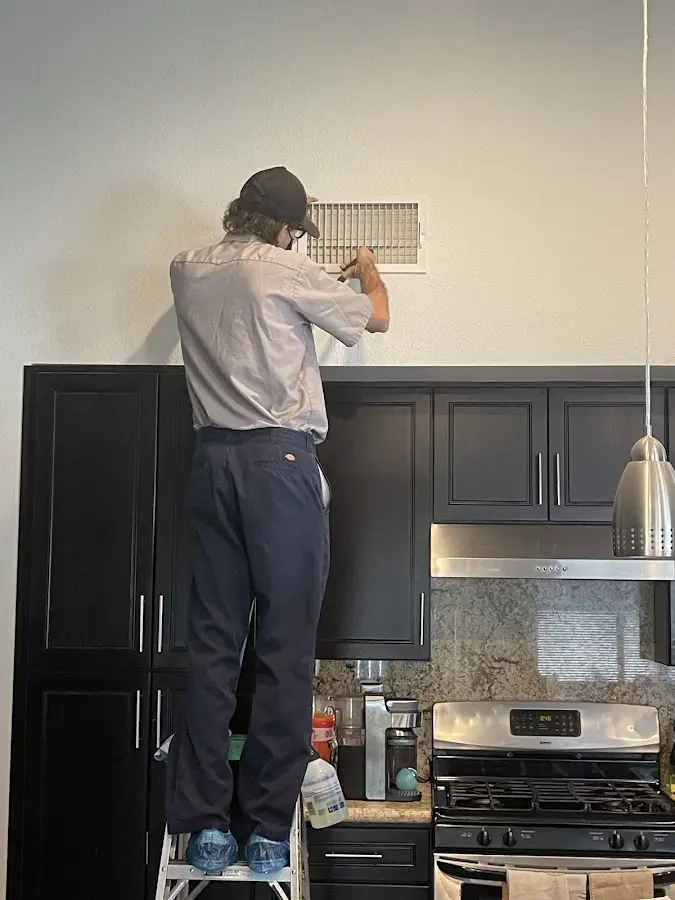 Technician inspecting an air vent during HVAC service in High Point
